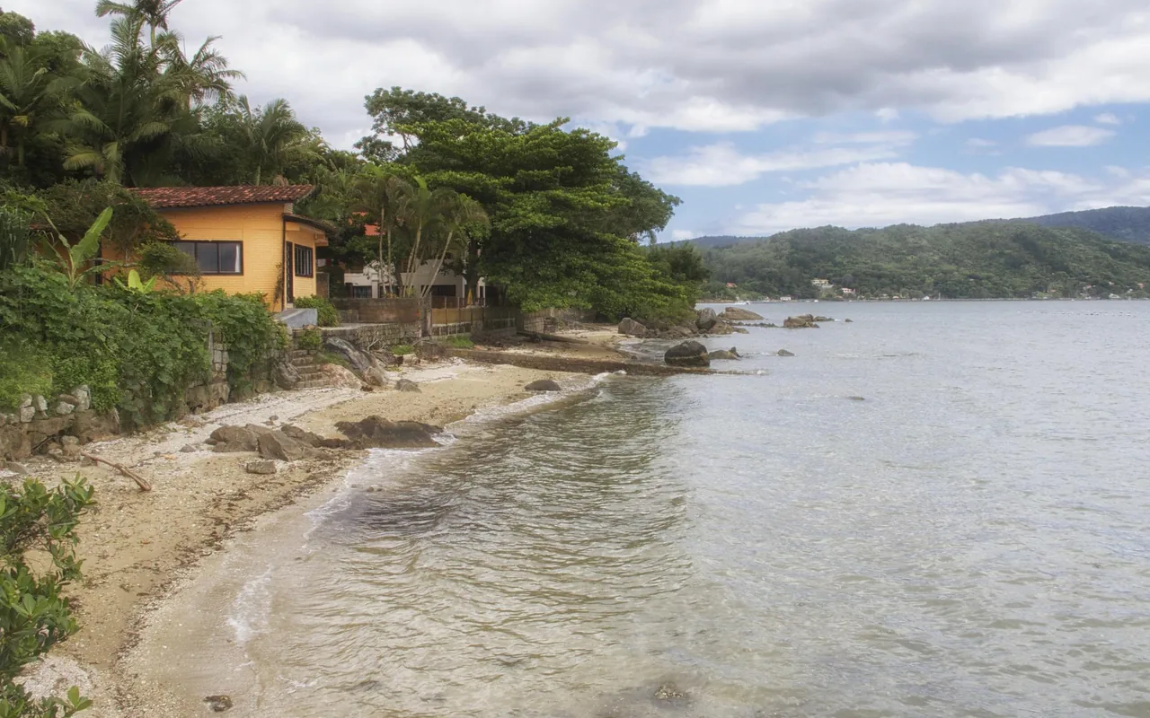 Orla de Sambaqui com pedras, árvores e casa amarela em janeiro de 2012