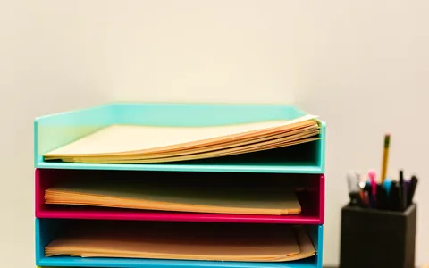Bandejas com documentos e materiais de escritório; fotografia ilustrativa de organização.