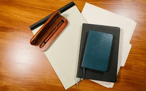 Papéis em branco, cadernos e caneta em fotografia ilustrativa.