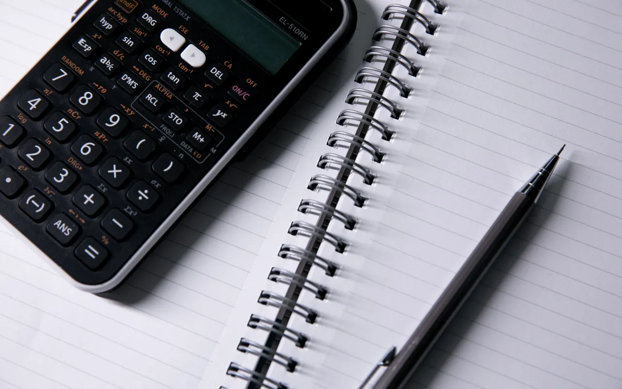 Calculadora e material de escrita em fotografia ilustrativa.