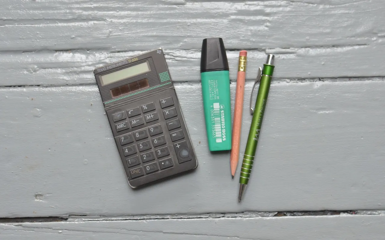 Calculadora e material de escrita em fotografia ilustrativa.